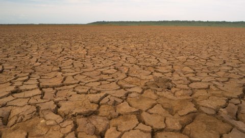 CLOSE UP: Big area of cracked soil caused by long draught. Brown desiccated land with ground cracks and no vegetation. Dry landscape with crack pattern caused by lack of water.