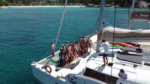 Phuket, Thailand, 19, December, 2020:
A large company poses on the bow of a sailing catamaran during a sea voyage to tropical islands, a large company on board a sailing boat