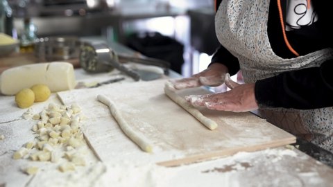 Mature woman working inside pasta factory doing fresh made gnocchi