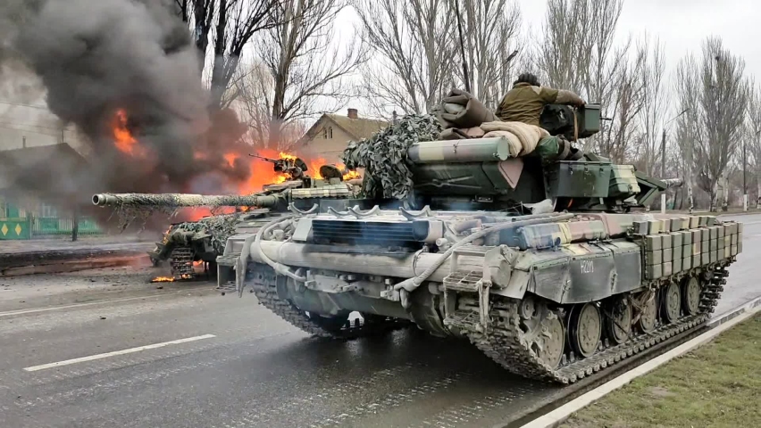 February 25, 2022. Melitopol, Ukraine, Zaporozhye region. Fighting in Melitopol. Ukrainian warriors drive tank along street past burning war machine during fight for city. War in Ukraine.