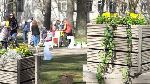 Olaine, Latvia - April 18, 2022. Urban landscape design with Easter decors and wooden decorative flower boxes in a town. April festive moods in the little city with family people.