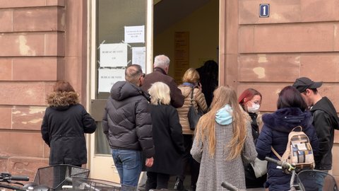 Paris, France - Apr 11: Street view of bureaux de Vote Voting section sign and people silhouettes queue to vote in the first round of the French presidential election in the city of Strasbourg, France