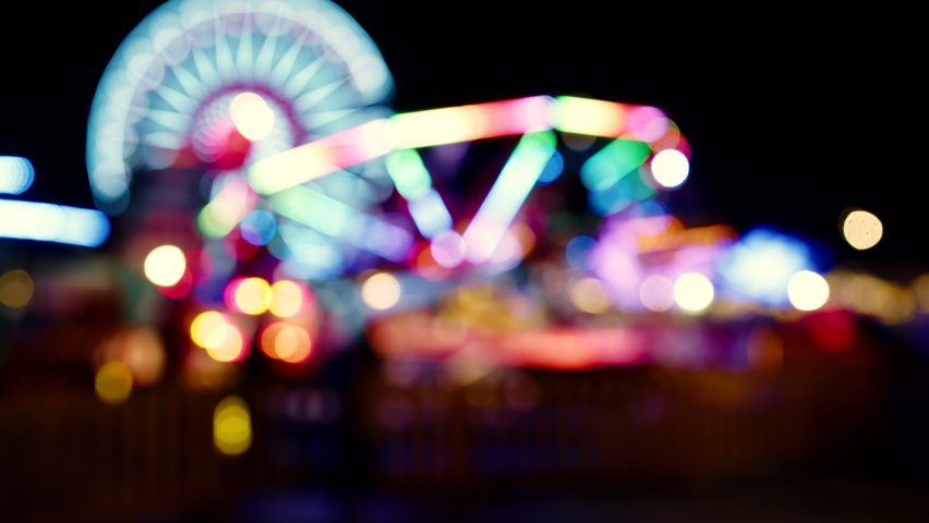 A blurred out view of a ferris wheel attraction at night in amusement park Royalty-Free Stock Footage #1089644875