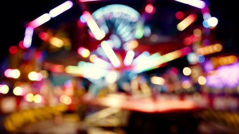 A blurred out view of a ferris wheel attraction at night in amusement park