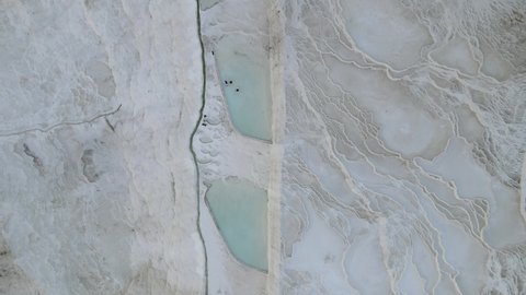 Drone view of Pamukkale travertines, natural beauty consisting of waterfalls and swimming pool with white minerals in Turkey, calcium white swimming pools in travertine