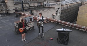 Drone view of a modern non-traditional rock band and a dog, who give an incendiary concert on guitars and a synthesizer on the roof
