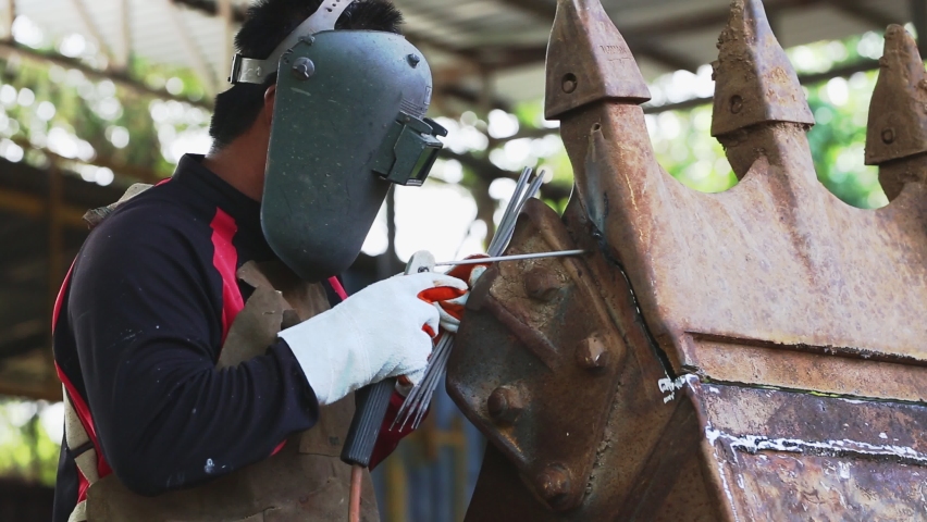 The man in the face mask is welded. Arc welding with co2, large metal part.