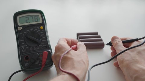 Man using a multimeter to measure the voltage of the batteries
