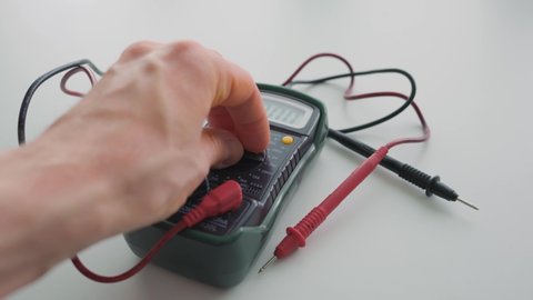 Man changing the measurement mode on a multimeter