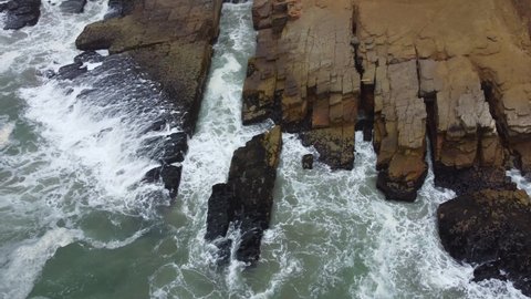 Drone footage of a rocky outcrop on a beach in Lima Peru.