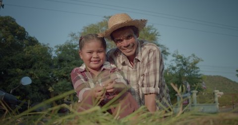 ็Happy smiling Asian daughter and father who are the native farmer family, has just cut the fresh grass to feed the cows.