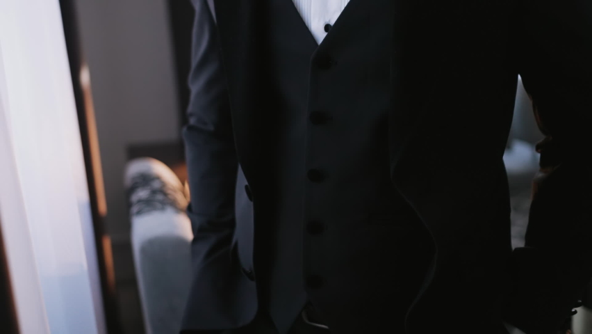 A successful person prepares for an important event and fixes his jacket. A man in a suit with a vest and a white shirt. The groom is preparing for the wedding ceremony. Caucasian man in the room