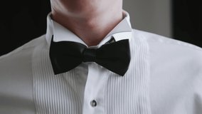 Successful elegant man going to a party and fixes bow tie around his neck by his hands. Element of men's wardrobe. Festive clothes for the official ceremony. - Powered by Shutterstock - Get 15% off with code: PIKWIZARD15