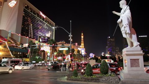 Las Vegas, USA - January 2016 : Statue of the Caesars Palace luxury hotel and casino at night, and cars on the Strip in Paradise, Nevada, United States