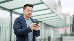 Senior Chinese tourist uses mobile phone app to book accommodation and call taxi, man near airport with suitcase. Asian man using smartphone app to rent a car at the bus stop. waiting public transport - Powered by Shutterstock - Get 15% off with code: PIKWIZARD15