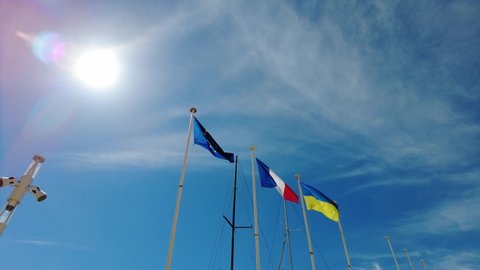 The Ukraine flag and European flag with France flag in the sun united in support of the Ukraine joining the European Union. isolated on blue sky background.