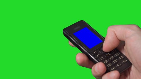 Person using old vintage mobile phone. Cellular with buttons. Black small cellphone telephone man holding in hands, push buttons. Isolated on green background isolated chroma key.