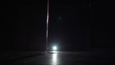 Pole dance in studio at black background. Striptease night club. Steel metal pole.