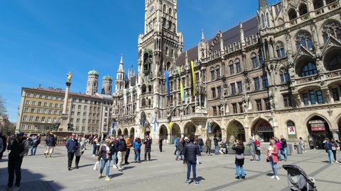 Munich, Germany 16.4.2022 Tourists walking in front of unique city hall in Munich city center. People sightseeing in front of tourist attraction in Marianplatz