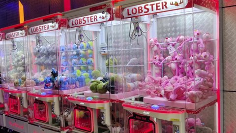 Kuala Lumpur,Malaysia - April 27,2022 : Panning view of the colorful arcade game toy claw crane machine where people can win toys and other prizes which is located in the shopping mall,Kuala Lumpur. 