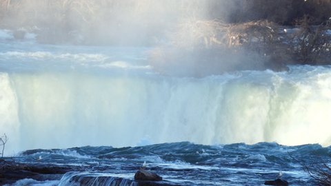 Mighty water running down the cliff of Niagara Horseshoe Falls, birds are flying and colonizing around the waterfalls