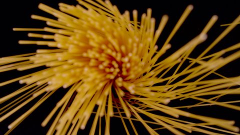 SUPER SLOW MOTION, CLOSE UP, PROBE LENS: Top down view of hand-dropped spaghetti on black background in slow motion. Falling spaghetti close up. Detailed view of scattered raw pasta.