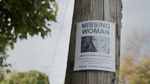 An advertisement for the missing woman hangs on a wooden pole. Search for missing people