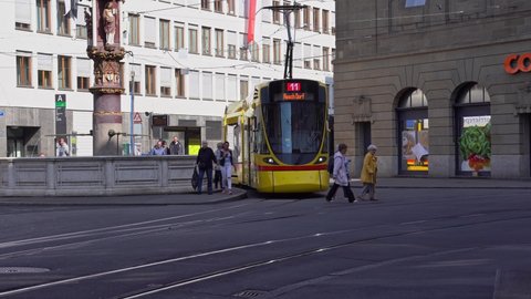 Yellow BLT tram at tram station Schifflände at the old town of Basel on a sunny spring day. Movie shot April 27th, 2022, Basel, Switzerland.