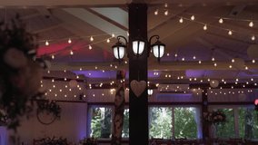 Wooden banquet hall with round forged lanterns on columns, beams with heart with stretched garlands and moving multi-colored lighting. Chandeliers suspended from roof rafters turn on and off. - Powered by Shutterstock - Get 15% off with code: PIKWIZARD15
