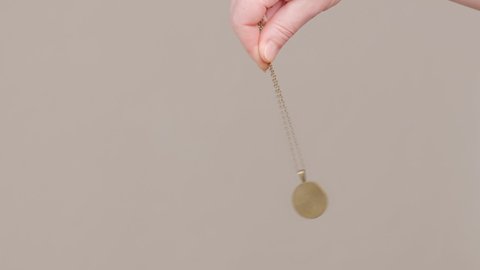 hypnosis session pendant on chain sways in female hand of hypnotist medium.