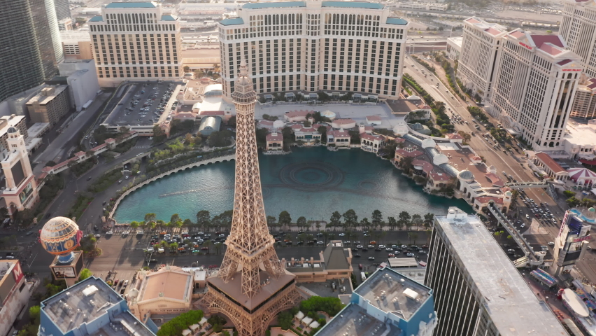 Las Vegas, Nevada USA April 2022. Aerial day video of Las Vegas Strip, Paris resort with closeup Eiffel tower overlooking busy street traffic and modern design hotel buildings with Bellagio fountains