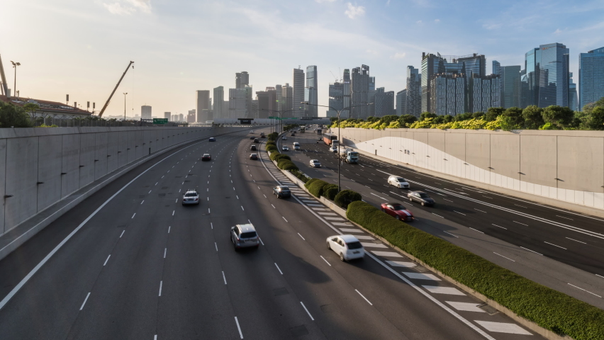 Time-lapse of car traffic transport on highway, financial district buildings, crane construction in Singapore at evening sunset. Asia transportation, commuter lifestyle, Asian city life concept