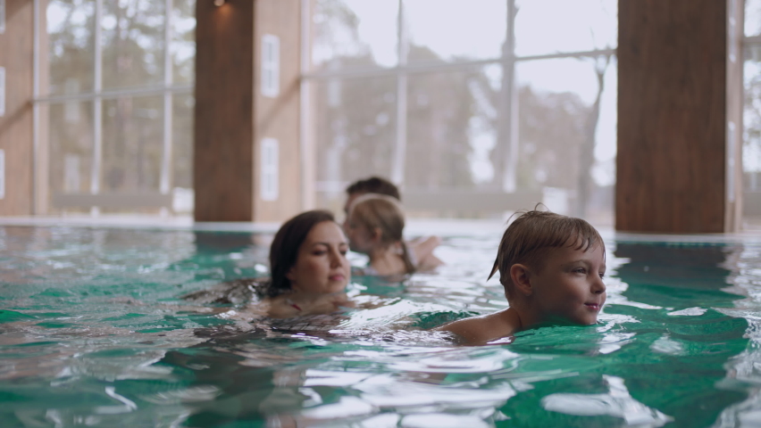 family weekend in hotel with indoor pool, children are swimming and parents are watching