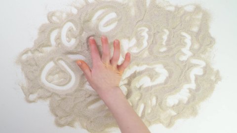 children hand playing in the sand. Top view draw on the sand. Caucasian hands write text in beige sand. Vacation and travel. Beach on vacation. Sand painting. Creativity from natural materials.