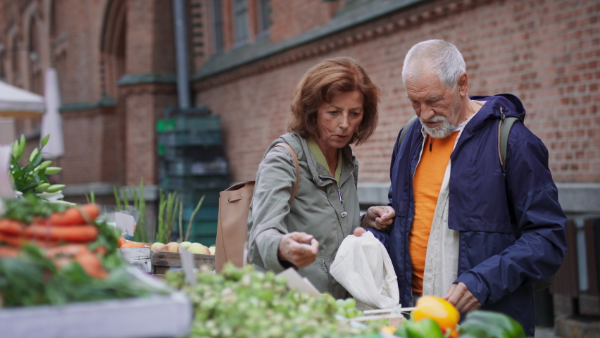 Happy senior couple tourists buying fruit outdoors on market in town. Royalty-Free Stock Footage #1089681263
