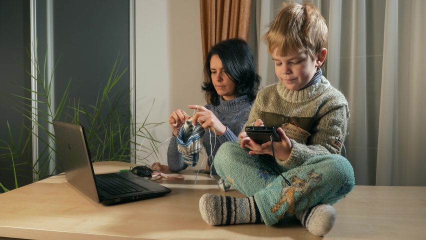 Child Kid Boy Use Watching Smartphone Internet Social Media. Mother Knit with Knitting Needles near Window. Cold Winter Season. 2x Slow motion 60fps 4K Royalty-Free Stock Footage #1089682909