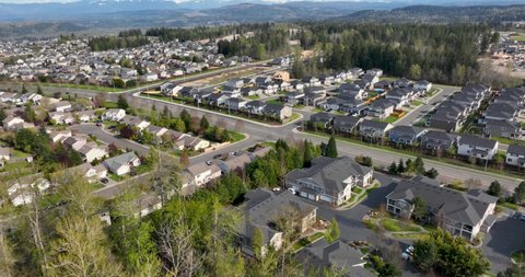 Aerial shot tiling up to reveal Mount Rainier with middle class houses in the foreground.