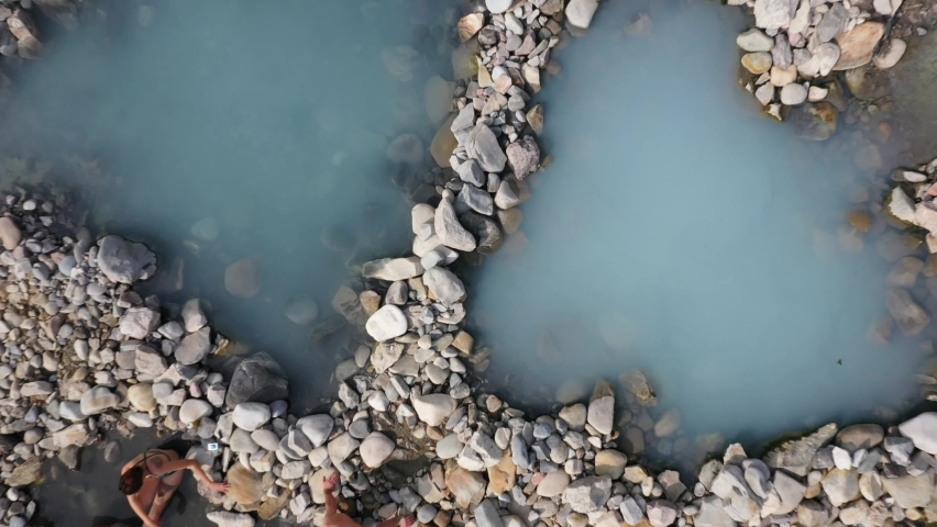 Top down View Of Tourists Relaxing On Rocky Shore of a hot spring in jackson, wyoming - drone shot