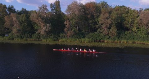Cinematic aerial view of eight rowing athletes rowing a boat on the river. sport leisure hobby rowing healthy lifestyle outdoors. Rowers are trained on the Dnieper River in the city of Kyiv, Ukraine.