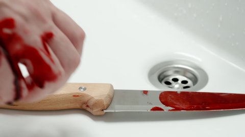 CRIMINAL: Man's bloodied hand puts a knife with traces of blood in the sink