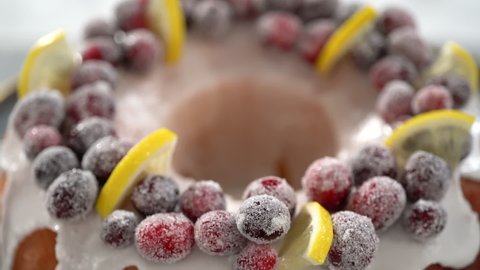 Step by step. Decorating lemon cranberry bundt cake with sugar cranberries and lemon wedges on a cake stand.