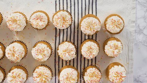 Flat lay. Arranging pumpkin spice cupcake decorated with Italian buttercream frosting and sprinkles on a cake stand.