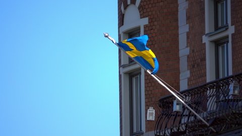 Lockdown Slow Motion Shot Of Swedish Flag Waving On Balcony During Sunny Day - Stockholm, Sweden