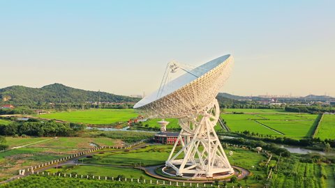 Aerial footage of astronomical radio telescope and beautiful sky clouds at sunset. Radio telescopes are used in science for space observation and distant objects exploring. Drone surround shooting.
