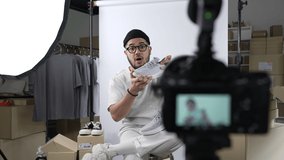 Young attractive Asian man blogger or vlogger looking at camera reviewing product and merchandise. Business online influencer on social media concept.