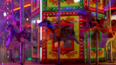 Horses going around a carousel in an amusement arcade at a fairground carnival