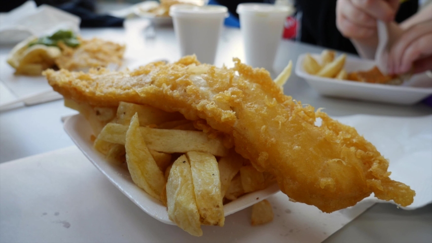 Family and friends eating fish and chips in a traditional English cafe chip shop Royalty-Free Stock Footage #1089706587
