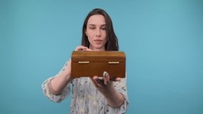 Shocked girl in a dress with an open wooden box in her hands stands on a blue background and looks with a surprised face