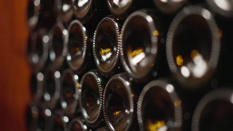 Wine bottle bottoms stacked in wine cellar indoors. Dark glass containers with high-quality alcohol beverage indoors in winery. Wine production concept