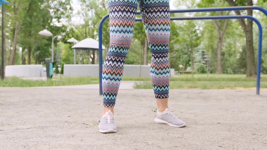 Pretty girl doing squats outdoors. Young woman exercising outside and make buttoms workout